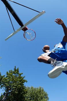 Young basketball player driving to the hoop for a high flying slam dunk. Shallow depth of field.