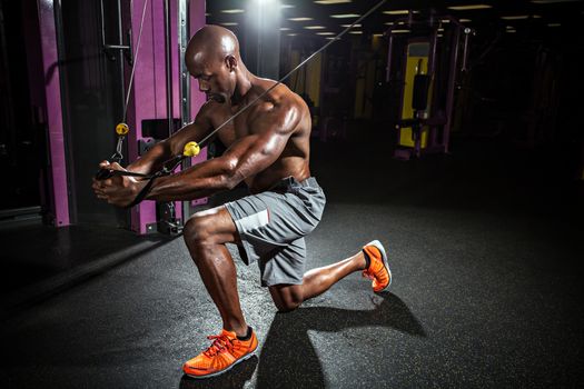 Muscular body builder working out  at the gym doing chest fly exercises on the cable wire machine.