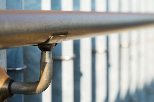 A metal railing on a metal fence with a shallow focus.