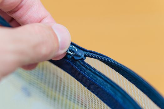 A close up shot of a hand pulling open the zipper of a small plastic pouch.