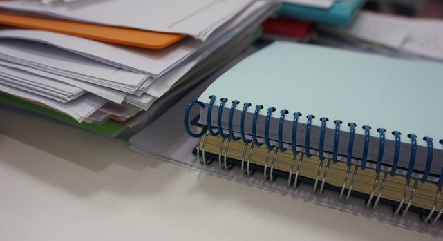 Notebook with a spiral spine and document placed on the desk in the office.                               