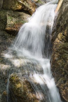 A waterfall running over and bouncing off of rocks.