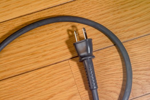 A gray electrical cord on a wooden floor.
