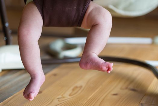 The feet and legs of a baby playing in a jumper.