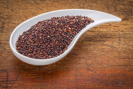 gluten free black quinoa grain grown in Bolivia ,  a teardrop shaped bowl against rustic grunge wood with a copy space