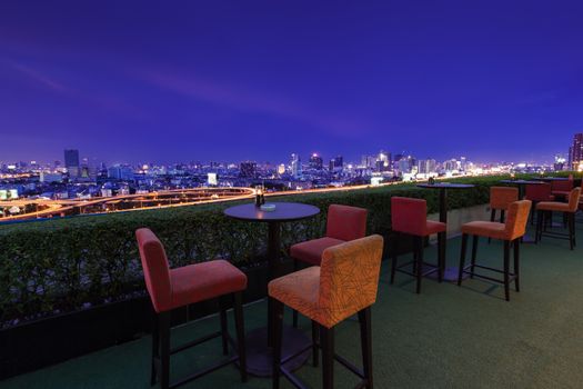 Restaurant dining table and view of business building on terrace at twilight evening time