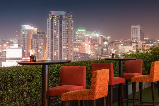 Restaurant dining table and view of business building on terrace at twilight evening time