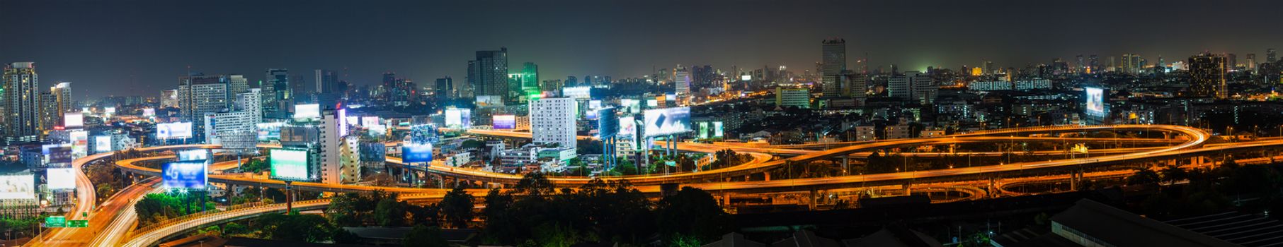 Light tail of Transportation car on road way at night life and Business Building Bangkok city area background as panorama, high angle birds eye view