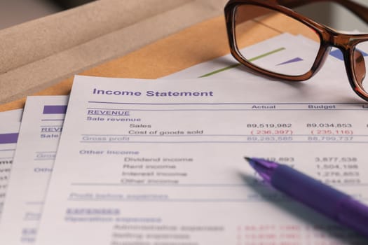 Income statement letter on brown envelope and eyeglass, pen,  business concept; document is mock-up