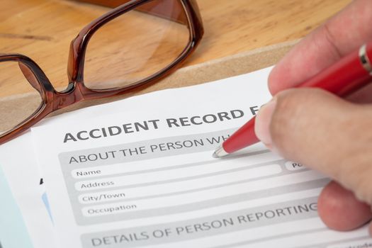 Accident report application form and human hand with pen on brown envelope and eyeglass, business insurance and risk concept; document is mock-up