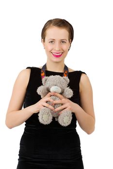 attractive smiling brunette holding teddy bear grimacing with peg on nose in a black dress, isolated on white