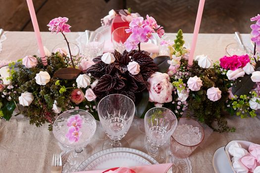 Festive wedding table setting with flowers, napkins, silver cutlery, glasses and candles