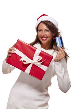 Attractive woman with a lovely smile wearing a red Santa hat holding a big red Christmas gift box and bank card as she celebrates her successful shopping spree
