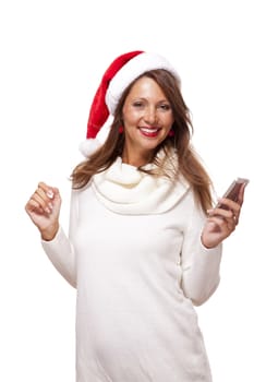 Pretty woman in a Santa hat reading a sms on her mobile phone sending Christmas wishes smiling with pleasure at the news, isolated on white