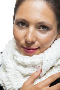 Attractive elegant woman in winter fashion snuggling down into her white scarf and black and white jumper to ward off the cold winter weather, on white