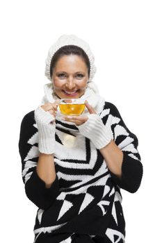 Elegant woman in a stylish black and white winter outfit with matching white mitts, scarf and knitted hat drinking a cup of hot tea, isolated on white