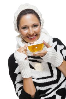 Elegant woman in a stylish black and white winter outfit with matching white mitts, scarf and knitted hat drinking a cup of hot tea, isolated on white
