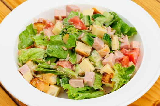 Appetizer salad with cheese, ham, fresh tomatoes, lettuce, sunflower seeds and crackers