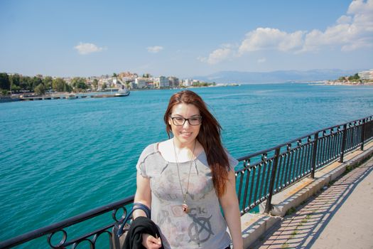 A young, beautiful caucasian girl posing in front of the sea in the beach of Chalkis city, Greece.