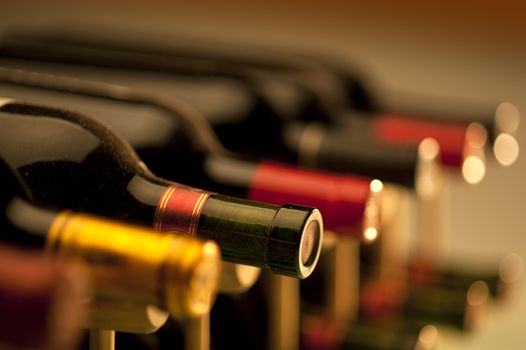 Red wine bottles stacked on wooden racks shot with limited depth of field