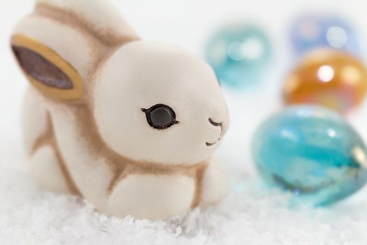 Easter bunny in the snow surrounded by colored eggs