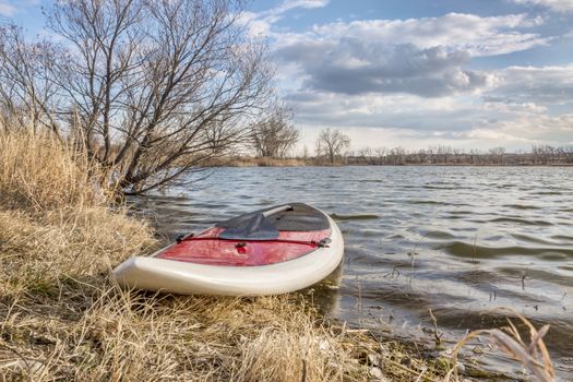 stand up paddleboard with a paddle on alke shore, early spring scenery - start of paddling season concept