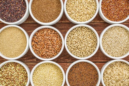 healthy, gluten free grains abstract (quinoa, brown rice, millet, amaranth, teff, buckwheat, sorghum), top view of small round bowls against rustic wood