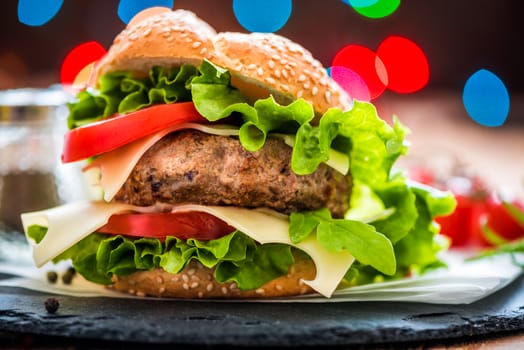 Closeup of Homemade Hamburger with Fresh Vegetables and Lights in Background