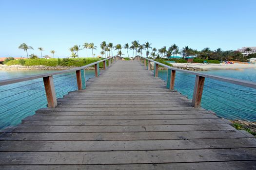 A wooden bridge over water going over to a beach