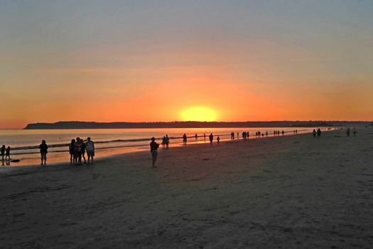 A sunset over the ocean with people enjoying the view