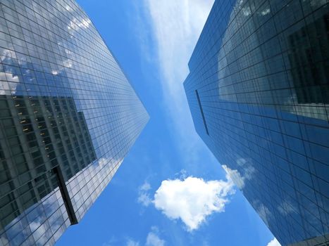 Looking up at two skyscrapers with blue sky