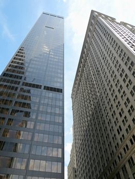 Looking up at two skyscrapers with blue sky