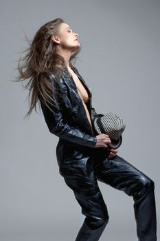 Woman in Leather Dress Holding a Hat and Hair Flying