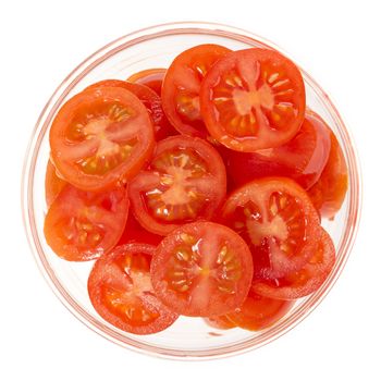 Sliced cherry tomatoes in glass bowl isolated on white, view from directly above.