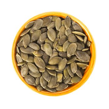 Raw shelled pumpkin seeds in orange bowl isolated and viewed from directly above.