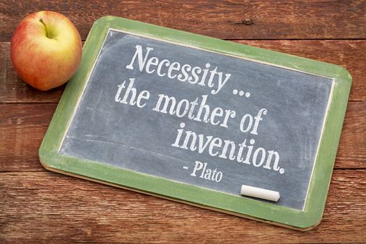 Necessity - the mother of invention  - Plato quote  on a slate blackboard against red barn wood