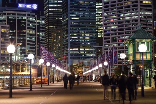 DARLING HARBOUR, AUSTRALIA - JUNE 4, 2015; Pedestrians walking across The Pyrmont Bridge, a swing bridge across Cockle Bay, Darling Harbour, towards Sydney and the CBD buildings and offices.