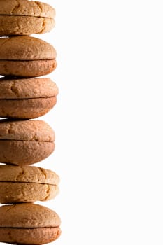 Food border of stacked freshly baked macaroons over a white background with copyspace in vertical format