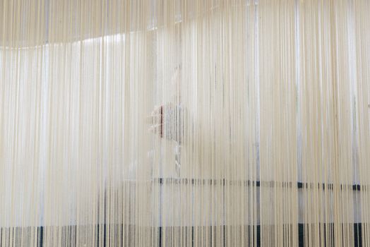 Unidentified woman working on a loom weaving a rug