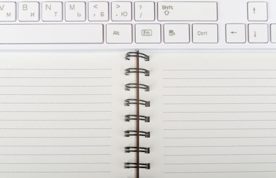 Keyboard and ring-bound notebook, close-up view