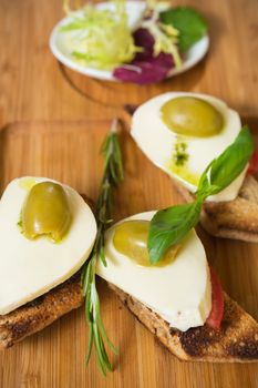 Bruschetta with tomato, mozarella and olive on wooden table 