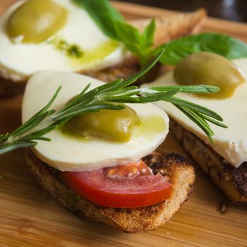 Bruschetta with tomato, mozarella and olive on wooden table 