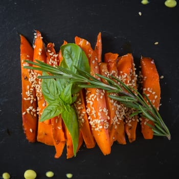 Caramelized carrots on black table. Shallow DOF