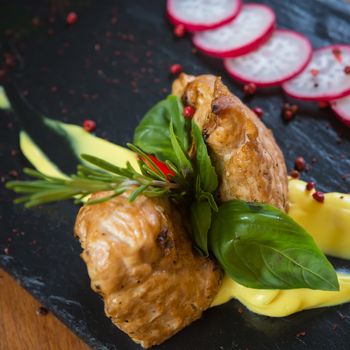 Grilled turkey steak on black board and brown wooden background