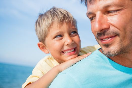 Closeup portrait og father holding son on his shoulders at the beach