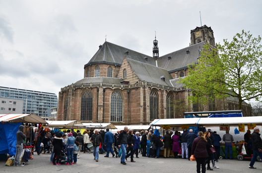 Rotterdam, Netherlands - May 9, 2015: People visit Street Market with Grotekerk (Big church) in Rotterdam. A large market is held in Binnenrotte, the biggest market square in the Netherlands.
