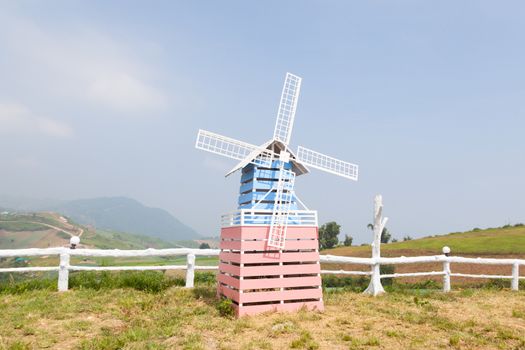 Wind turbines. Made of wood on the grass near the fence.