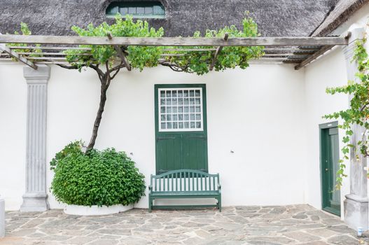 Grape vine, bench and window with barn doors at the historic  Drosdy, built by the Dutch East India Company in 1747