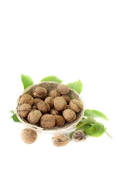 walnuts with walnut leaves in a basket on bright background