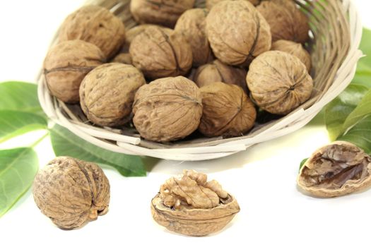 fresh walnuts with walnut leaves in a basket on bright background